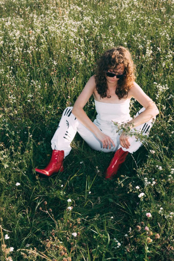 Frau sitzt im Gras mit roten Schuhen
