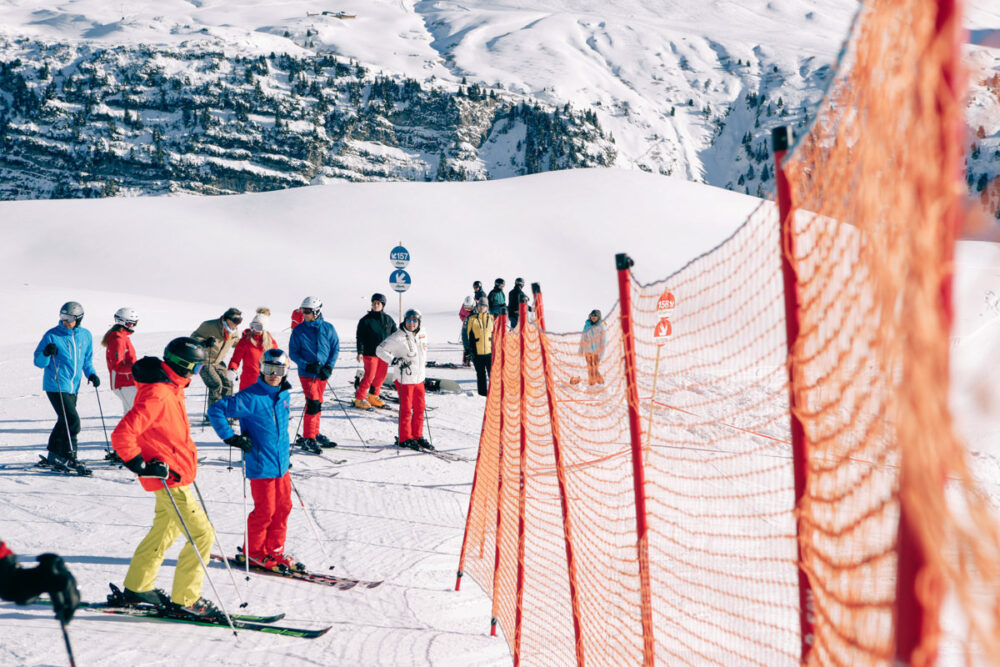 orangener Zaun auf Skipiste mit Personen bei Alpinsport