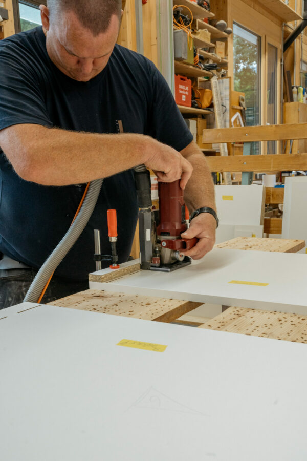 ein Mitarbeiter der Tischlerei Längle bearbeitet ein Holzplatte